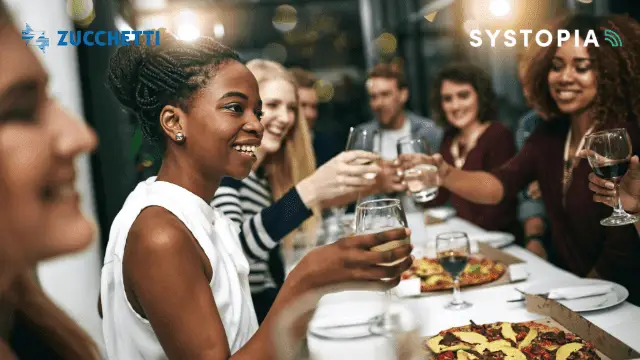 An image of work colleageues sitting around a tables and toasting with wine glasses. This image illustrates the outcome of using TCPOS loyalty schemes in corporate hospitality.